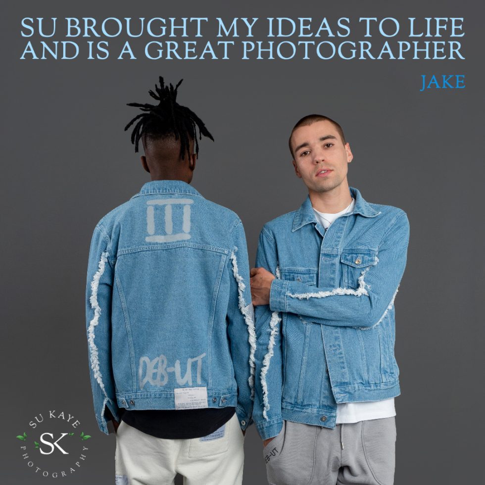 Two men in denim jackets facing away, showing the backs of their jackets with unique designs, in a promotional photo for a photographer named su kay.