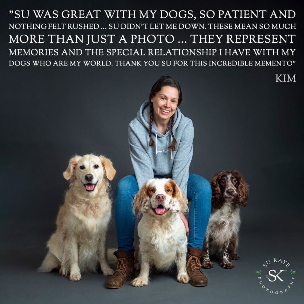 A woman smiling, sitting on the ground with four dogs around her, in a portrait by su kaye photography, with a heartfelt testimonial overlay.